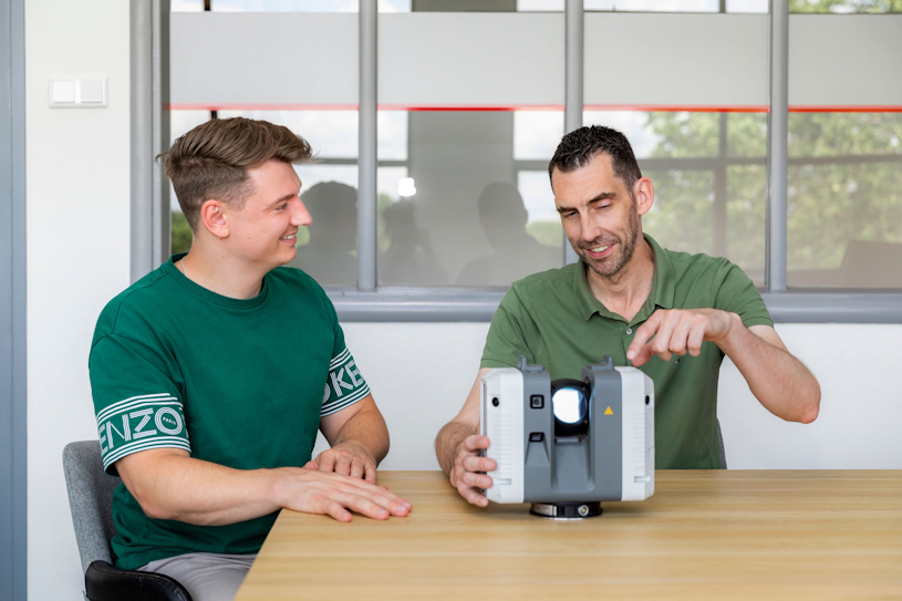 Medewerker die functies van de Leica RTC360 3D laserscanner aan het uitleggen is aan een collega. Gericht op de verkoop van de laserscanner.